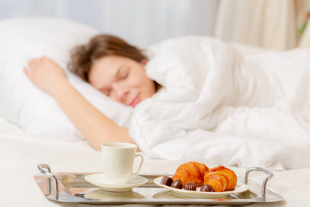 Jeune femme endormie et plateau avec son petit déjeuner dans la chambre
 - Photo, image
