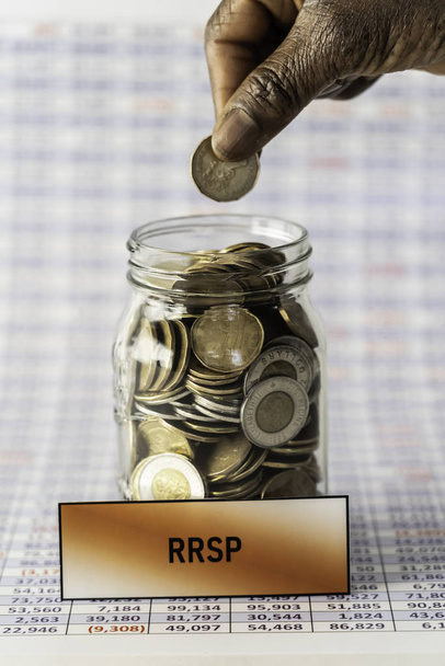 African American Nigerian woman dropping coins into RRSP jar - Photo, Image