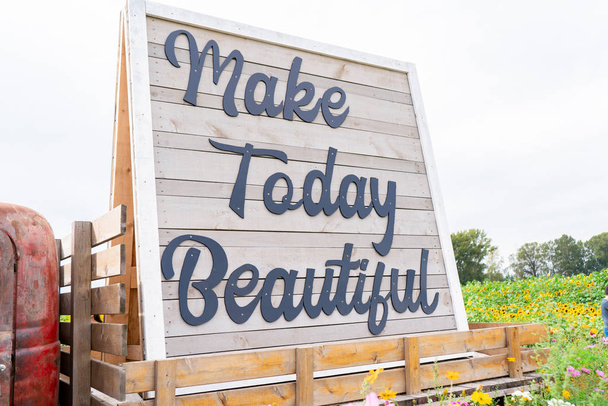 Drewniany napis na ciągniku, który mówi Make Today Beautiful w kursywnym piśmie na polu kwiatów - Zdjęcie, obraz