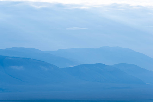 Gentle hills in bluish haze. Soft light in early morning, silhouettes of mountains - Valokuva, kuva