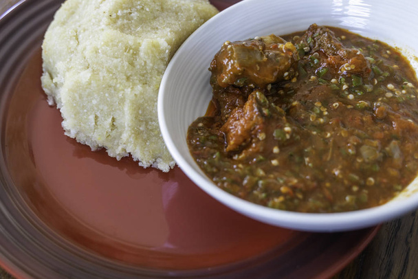 ナイジェリアのスパイシーなオクロとペッパーのシチューは、食べる準備ができてEbaで提供 - 写真・画像
