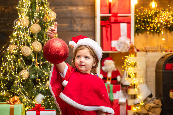 Decoración infantil de Navidad con adorno o bola de Navidad. Juguete de Navidad - chica está decorando el árbol de Navidad
. - Foto, imagen