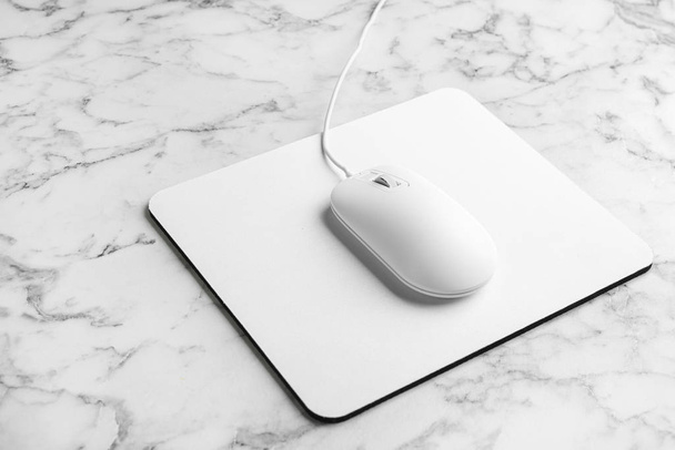 Modern wired optical mouse and pad on white marble table - Foto, Bild