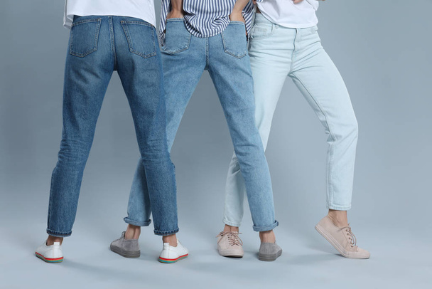 Group of young women in stylish jeans on grey background, closeu - Φωτογραφία, εικόνα
