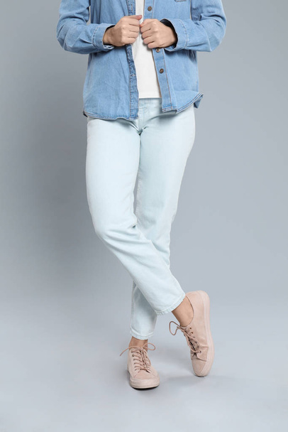 Young woman in stylish jeans on grey background, closeup - 写真・画像