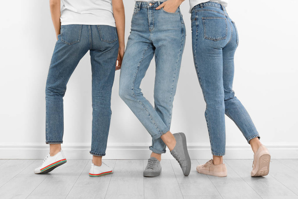 Group of young women in stylish jeans near white wall, closeup - Foto, Bild