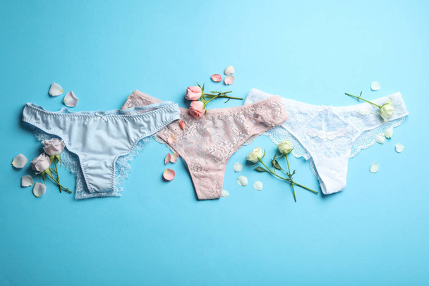 Set of elegant women's underwear and flowers on light blue background, flat lay - Foto, afbeelding