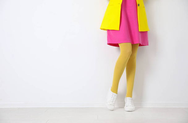 Woman wearing yellow tights near white wall, closeup. Space for text - Valokuva, kuva