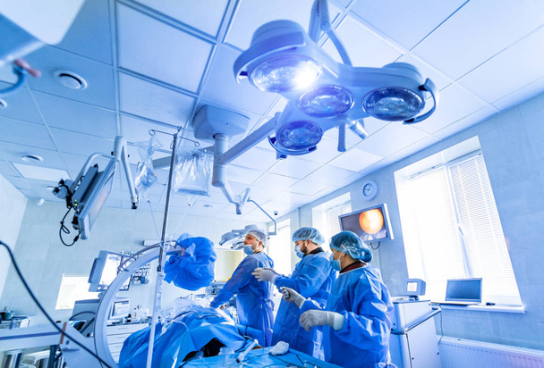 Medical team performing surgical operation in bright modern surgery room. Operating theatre. Modern equipment in clinic. Emergency room. - Foto, immagini