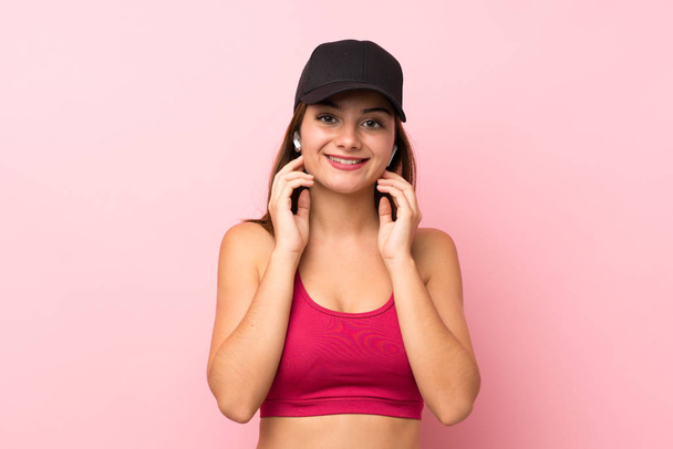 Young sport girl over isolated pink background listening music and looking to the front - Fotografie, Obrázek