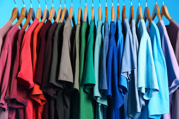 Kolorowe ubrania na wieszakach na jasnoniebieskim tle - Zdjęcie, obraz