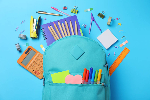 Stylish backpack with different school stationery on light blue background, flat lay - Foto, Imagem