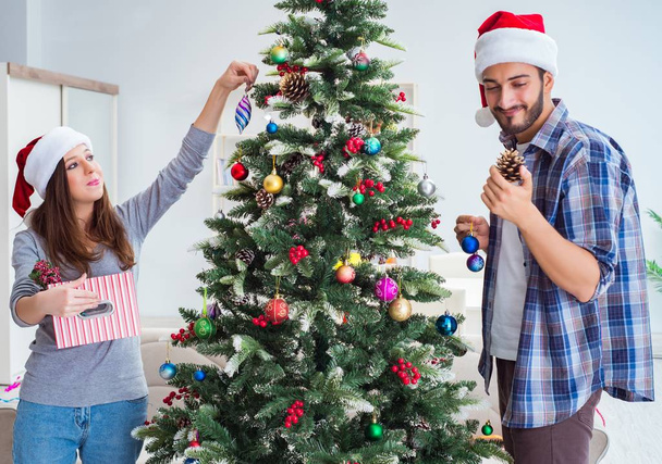 Fiatal család díszítő karácsonyfa boldog alkalomra - Fotó, kép