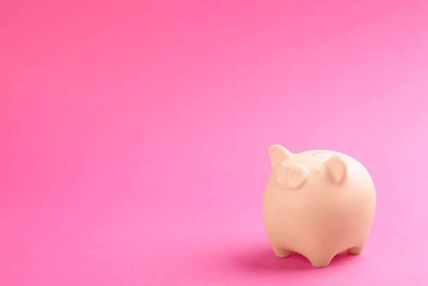 Beige piggy bank on pink background. Space for text - 写真・画像
