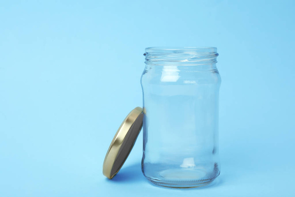Open empty glass jar on light blue background, space for text - Foto, Imagem