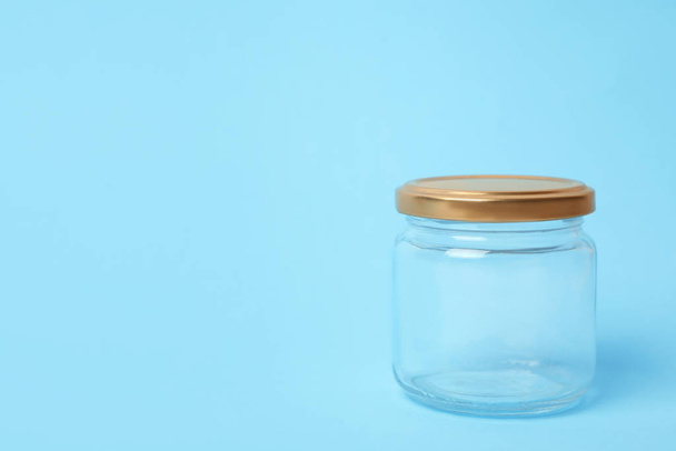 Closed empty glass jar on light blue background, space for text - Фото, изображение