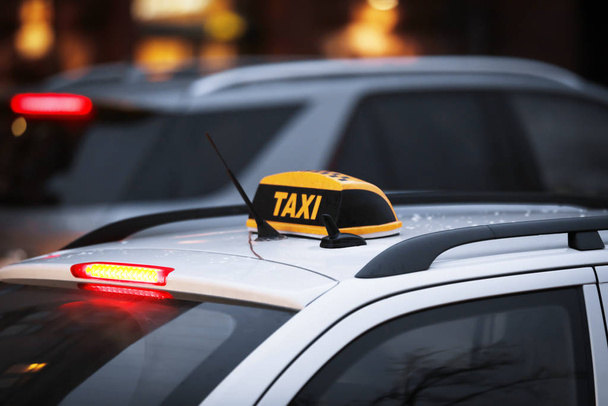 Taxi voiture avec panneau jaune à carreaux sur la rue de la ville dans la soirée
 - Photo, image