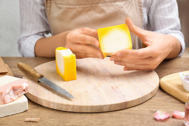 Woman holding natural handmade soap at wooden table, closeup - Foto, Imagen