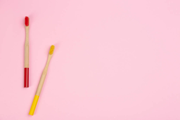 Toothbrushes made of bamboo on pink background, flat lay. Space  - Foto, afbeelding