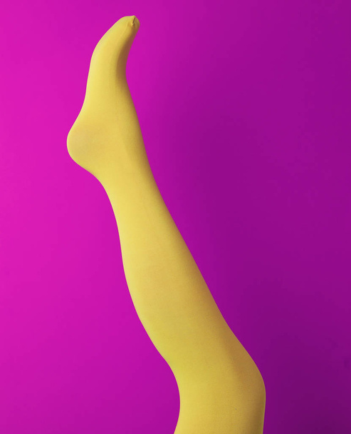 Leg mannequin in yellow tights on purple background - Fotó, kép