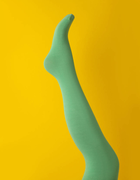 Leg mannequin in green tights on yellow background - Foto, afbeelding