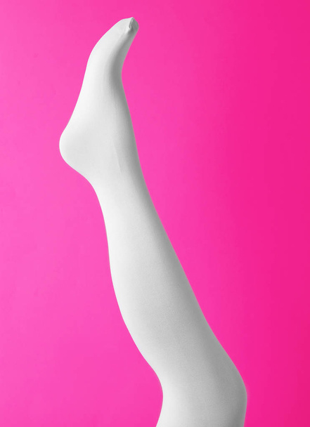 Leg mannequin in white tights on pink background - Foto, afbeelding