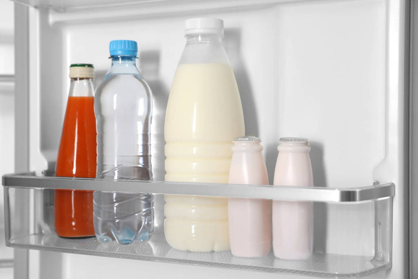 Different bottles in basket of modern refrigerator - Foto, Imagen