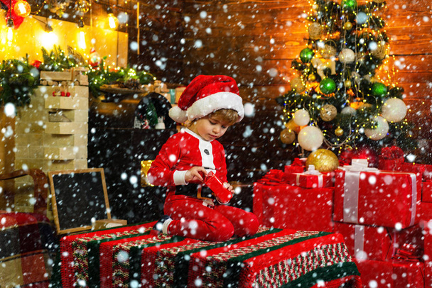 Kluk ve sněhu. Chlapec roztomilé dítě veselá nálada hrát poblíž vánoční strom. Veselé a veselé Vánoce. Počáteční dárek. Krásné dítě si užije Vánoce. Santa chlapec malé dítě slaví Vánoce doma. Rodina - Fotografie, Obrázek