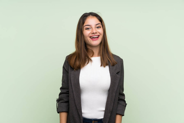 Young brunette girl with blazer over isolated green background with surprise facial expression - Фото, зображення