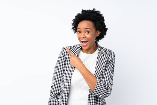 Mujer afroamericana con chaqueta sobre fondo blanco aislado sorprendido y apuntando lado
 - Foto, imagen