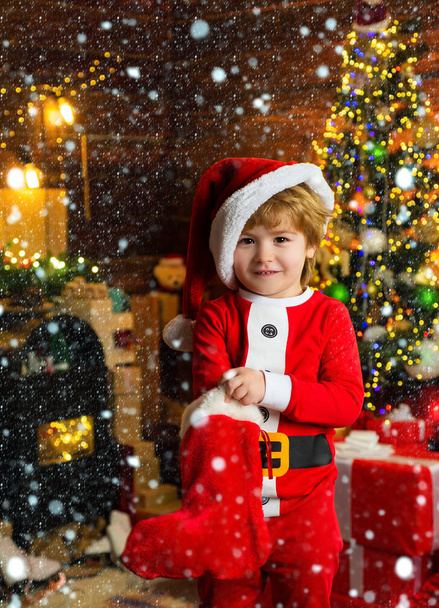 Childhood moments. Kid boy santa hold christmas gift. Christmas stocking concept. Child cheerful face got gift in christmas sock. Contents of christmas stocking. Oh happy day. Joy and happiness. Child - Photo, Image