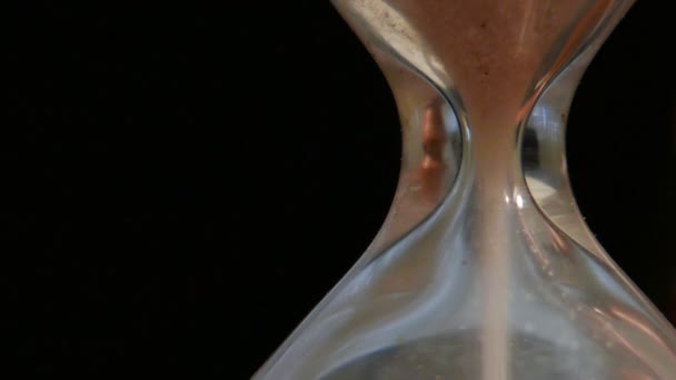 zandloper tellen van de tijd in extreme close-up, zwarte achtergrond - Video