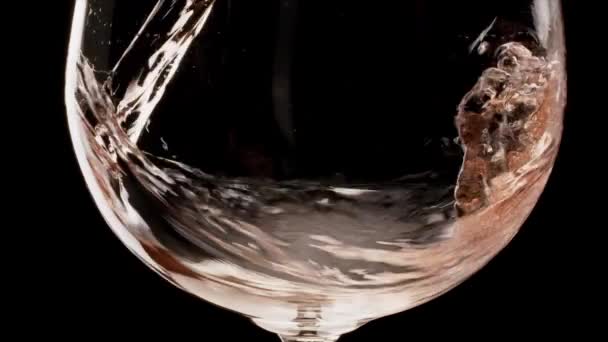 Różowe wino wlewa się do szklanki na czarnym tle. Mało brakowało. Kamera Blackmagic 6k. - Materiał filmowy, wideo