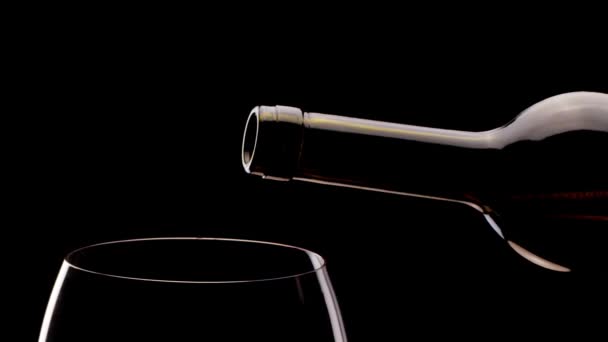 Il vino rosso da una bottiglia versa in un bicchiere su uno sfondo nero. Un tiro ravvicinato. Macchina fotografica 6K Blackmagic
. - Filmati, video