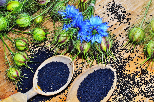 Black cumin (nigella sativa or kalonji) seeds in heart-shaped bowl on wooden background - Photo, Image