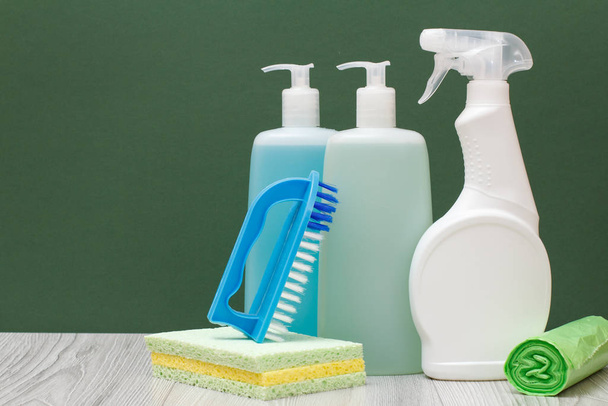 Bouteilles de liquide vaisselle, nettoyant pour vitres et carreaux et éponges sur fond vert
. - Photo, image