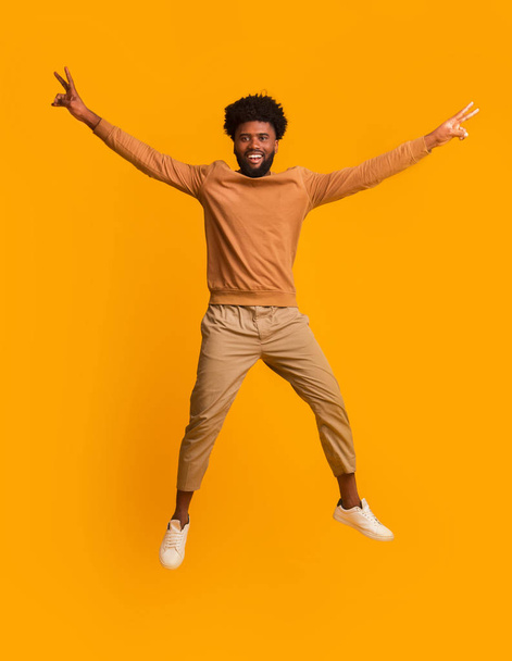 Black cheerful guy jumping up with raised hands - Valokuva, kuva