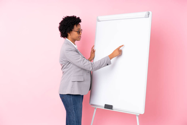 Afrykański amerykański biznes kobieta dając prezentację na białej planszy na odizolowanym różowym tle dając prezentację na białej planszy - Zdjęcie, obraz