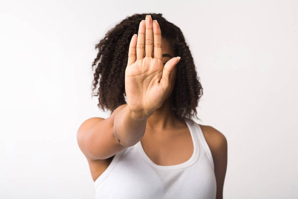 Молодая черная девушка показывает знак стоп на белом фоне
 - Фото, изображение