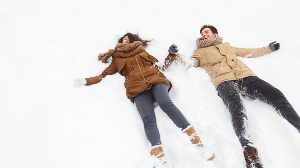 Happy Couple Lying In Snow Laughing Holding Hands Outdoor, Panorama - Photo, Image