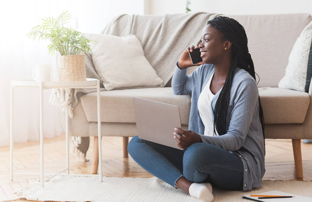 Black Girl Sitting On Floor, Talking On Cellphone And Using Laptop - Fotografie, Obrázek