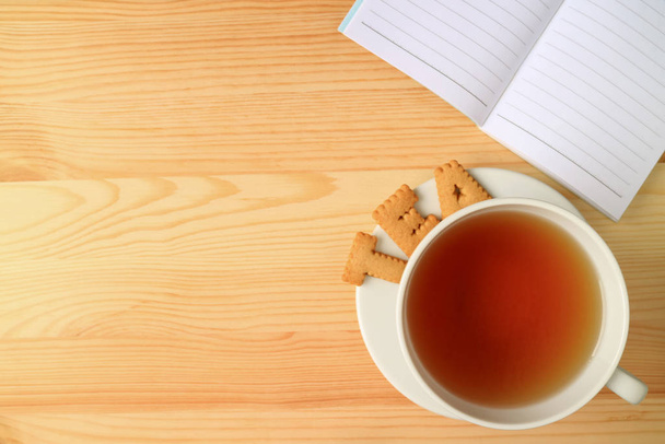 熱いお茶のカップとクッキーで作られた言葉のお茶のトップビュー,木製のテーブルの上にラインノートペーパーで - 写真・画像