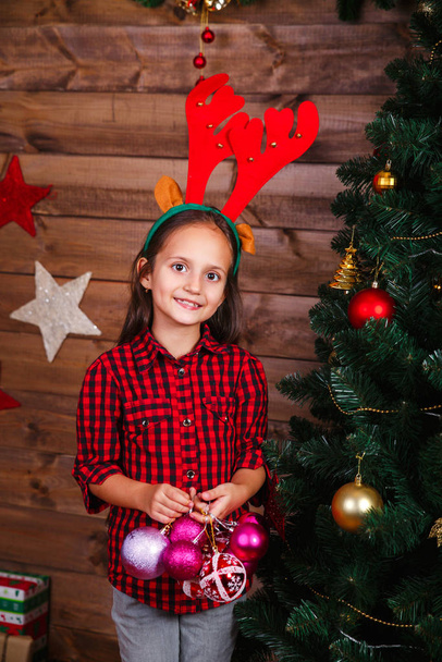 Cute little girl decorating Christmas tree with colorful toys at home - Foto, Bild