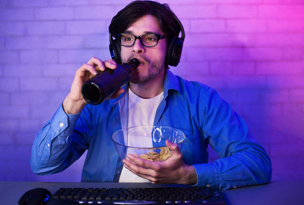 Konzentrierte Spieler trinken Bier mit Chips, schauen auf den Bildschirm - Foto, Bild