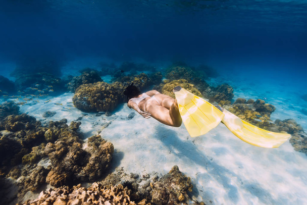 Free plongeur jeune fille avec des nageoires jaunes glisse sur fond sablonneux
  - Photo, image