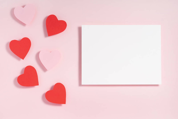 Valentine's day frame composition. Red pink hearts blank sheet of paper on pastel pink background. Top view, flat lay, copy space - Zdjęcie, obraz