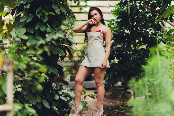 pretty young woman gardening in an apron, without clothes. - Foto, Imagem