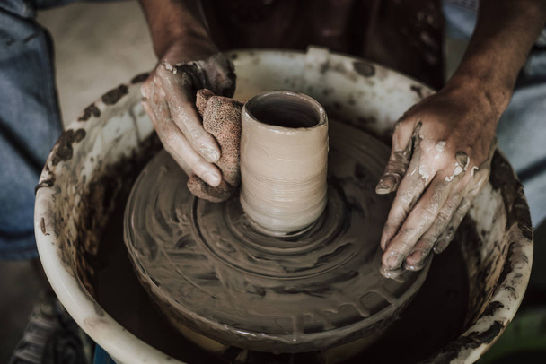 Hands of craftsman artist working on pottery wheel. - Fotó, kép