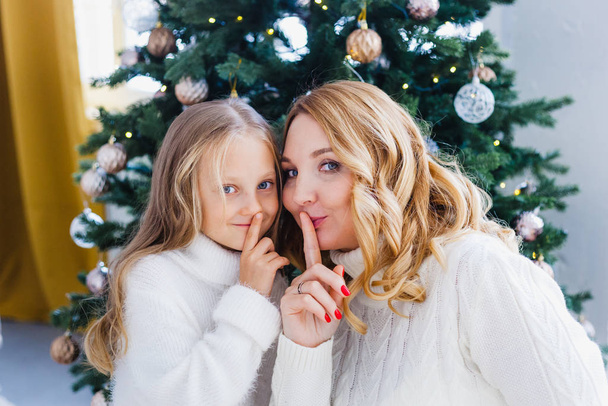 Una niña con su madre cerca del árbol de Navidad, el interior decorado para el nuevo año y la Navidad, la familia y la alegría, tradiciones - Foto, Imagen