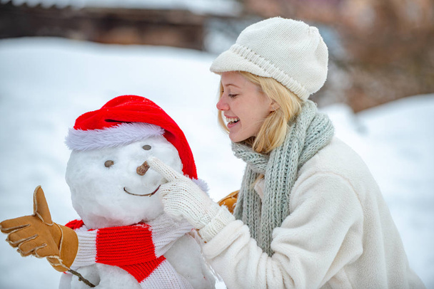 Miluju zimu. Šťastná usměvavá dívka, aby sněhulák na slunné zimní den. Šťastný zimní čas. Šťastný sněhulák stojící v zimě vánoční krajina. - Fotografie, Obrázek